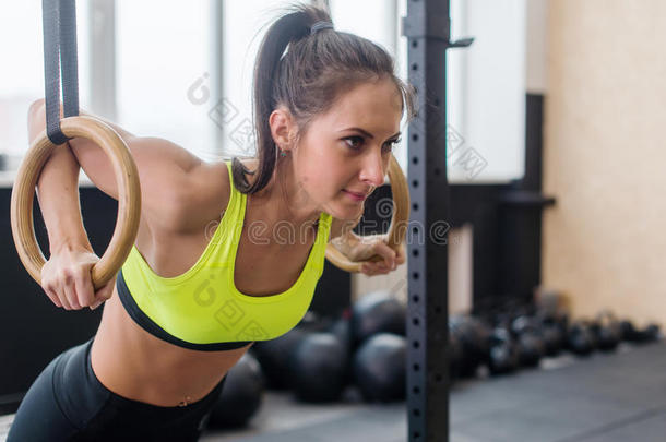 健身妇女做俯卧撑训练手臂与体操戒指在健身房的概念，锻炼健康的生活方式运动。