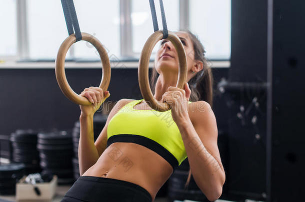 运动员适合妇女在健身房锻炼，拉上体操环。
