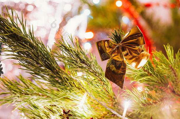 金色的蝴蝶结在绿色圣诞树树枝的背景上