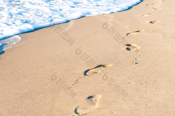 日落时沙滩上的脚印。 暑期旅游概念