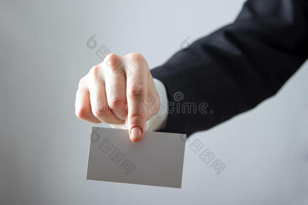 双手拿着白色的商务名片，礼物，门票，通行证，呈现在模糊的蓝色背景上。 复制空间