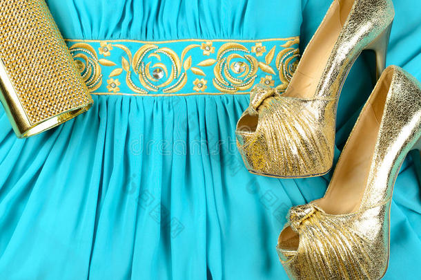 金色高跟鞋，离合器袋和蓝色连衣裙与金色口音。 上面的风景