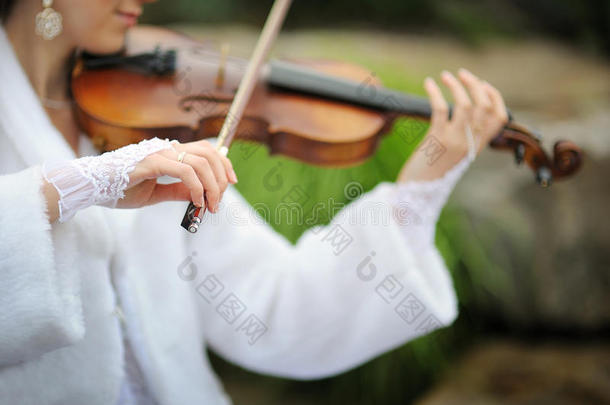 新娘在夏季公园为新郎拉小提琴