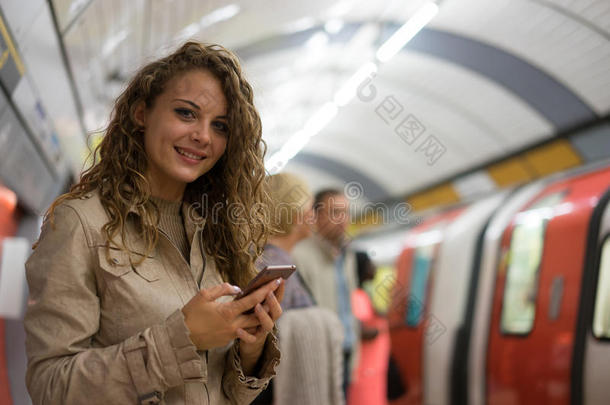 一个在地铁地铁站用手机的女人，洛