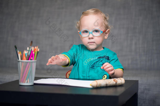戴眼镜的孩子坐在桌子后面的桌子旁做眼科检查