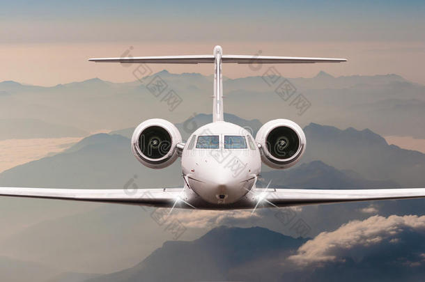 飞机在日落时飞过云层和阿尔卑斯山。 大型客机或货机的正面视图，商务喷气式飞机