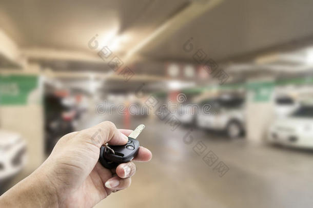 手男亚洲人，拿着汽车遥控器在模糊的图像上停车