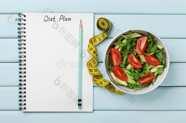蓝色背景下新鲜沙拉的饮食计划、菜单或程序、卷尺、水和饮食食物、减肥和排毒概念