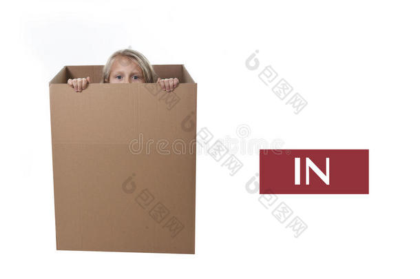 可爱可爱的金发孩子躲在纸板箱里，在白色背景上孤立地学习英语介词
