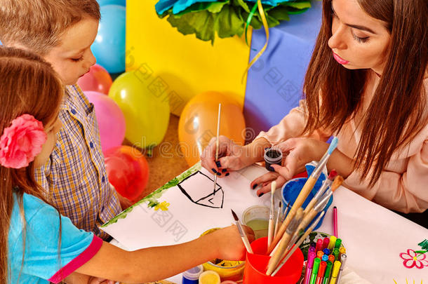 幼儿园里带着女教师在纸上画画的孩子。