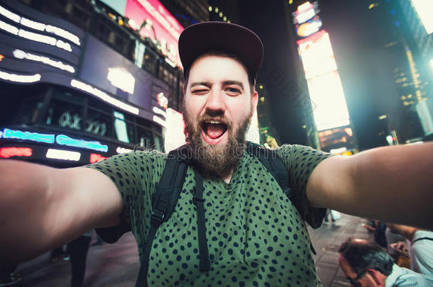 有趣的胡须男子背包客微笑和自拍照片在纽约时代广场，而旅行<strong>跨越</strong>美国