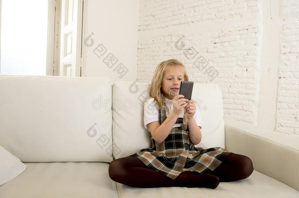 <strong>女孩子</strong>金发坐在沙发上，使用手机上的互联网应用程序