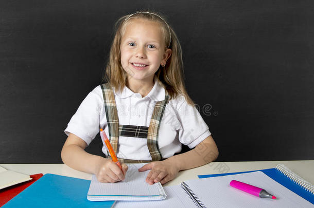 美丽快乐的金发女<strong>初中</strong>生在做学校作业时微笑着用钢笔在记事本上写字