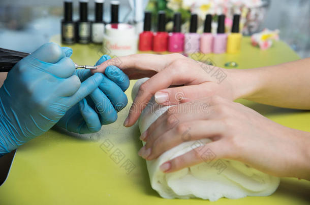 一位在美甲沙龙接受指甲锉美容师修剪指甲的妇女的特写镜头。 去修指甲的女人