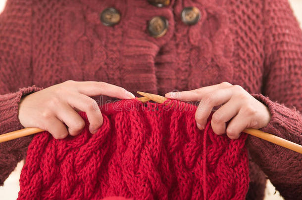 特写妇女的手拿着木制编织针，在红领巾上工作