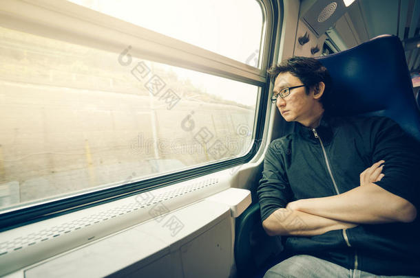 英俊的亚洲男人透过火车窗口看，温暖的灯光色调，有复制空间