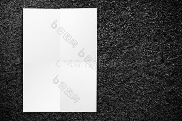 黑色折叠白纸<strong>海报</strong>挂在黑色石墙上，模板模拟添<strong>加</strong>您的文本。