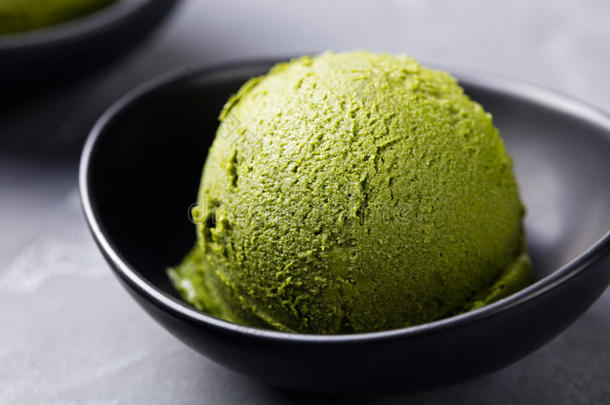 绿茶<strong>抹茶冰淇淋</strong>勺在碗中的灰色石头背景。