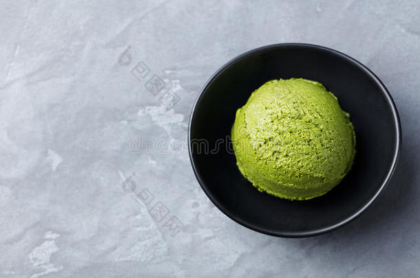 绿茶抹茶冰淇淋勺在黑色碗在灰色的石头背景。 复制空间顶部视图