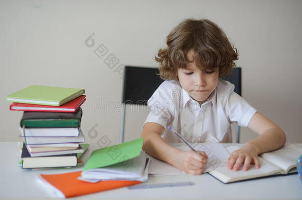 男孩坐在学校的桌子上勤奋地做作业