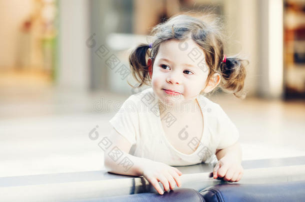 可爱可爱的可爱微笑的白人白种人蹒跚学步的女孩的特写肖像，深棕色的眼睛和卷曲的辫子