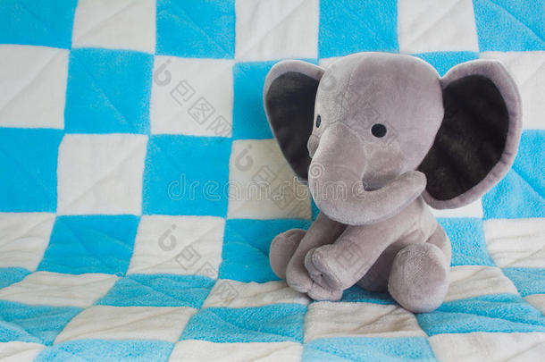 可爱的小象填充动物在蓝色格子毯子上