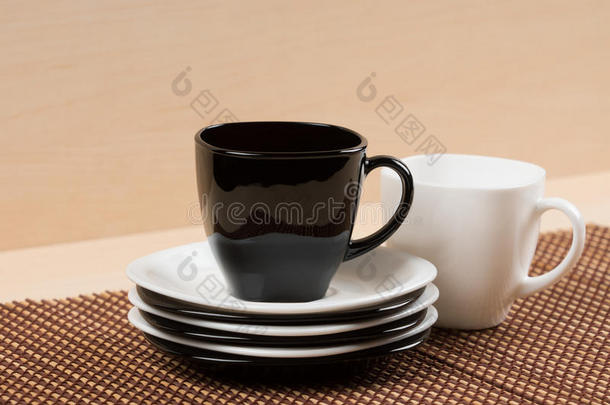 近景的红茶杯在堆叠的白色和黑色盘子附近的白色茶杯在桌面上。