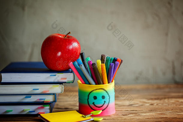 一组学习用品和书籍以及背景上的红苹果。学校，文具，设备。