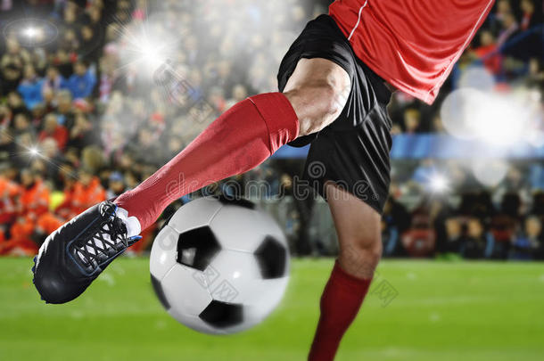 关闭足球运动员的腿和足球鞋在行动踢球在体育场比赛