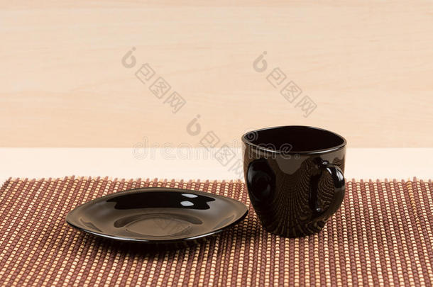 红茶杯站在桌子上的黑色盘子附近。