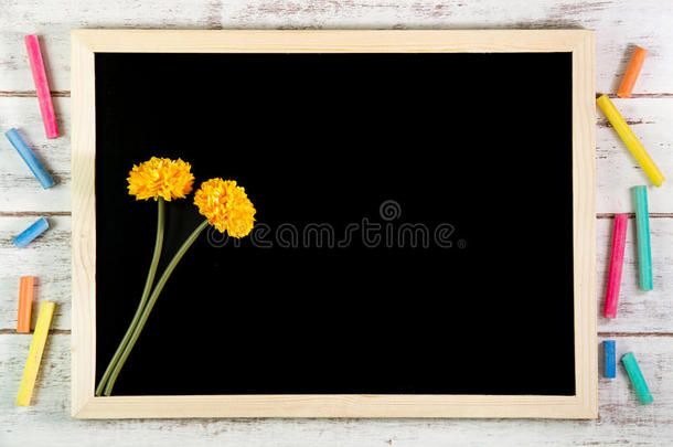空白<strong>黑板</strong>和木制桌子上的黄色塑料花。<strong>模板</strong>模拟添加您的设计，并在框架旁边留下空间