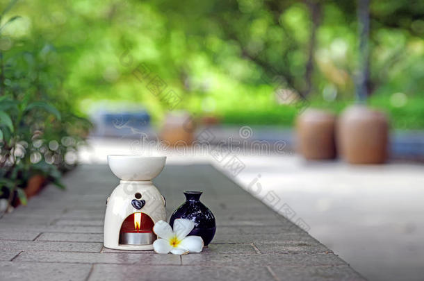 香薰油燃烧器与Frangipani花和香薰油瓶在旁边。香薰油燃烧器在
