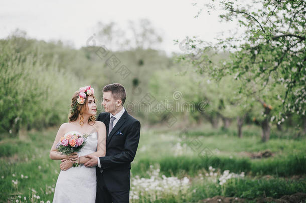 美丽的新娘穿着婚纱，戴着花束和玫瑰花环，和新郎一起穿着婚纱