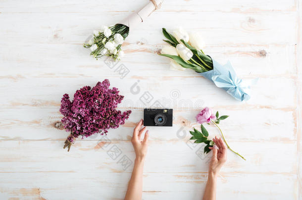 女人的手把花和照片相机放在桌子上