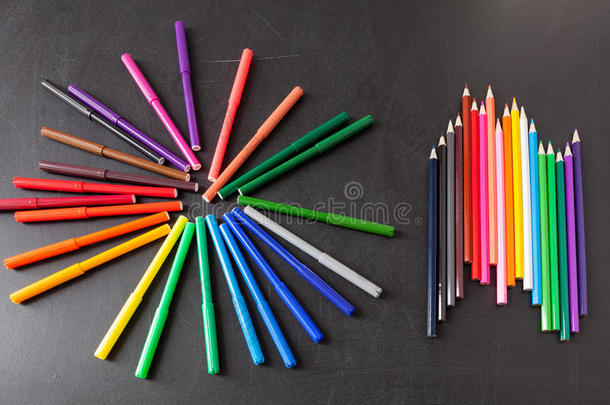 彩色铅笔排在黑色学校黑板上作为背景，概念回到学校