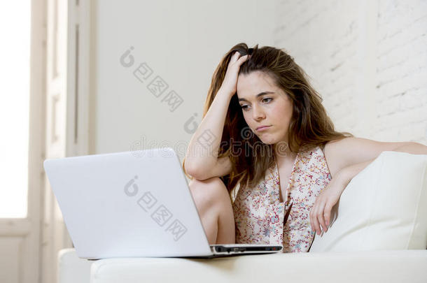 失望的女孩在家里沙发上使用互联网学习笔记本电脑