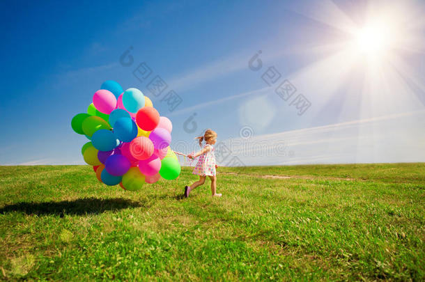 拿着彩色气球的小女孩。在果岭上玩耍的孩子