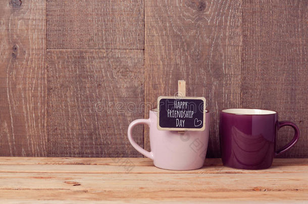 木桌上有黑板标志的咖啡杯。 友谊日庆祝活动