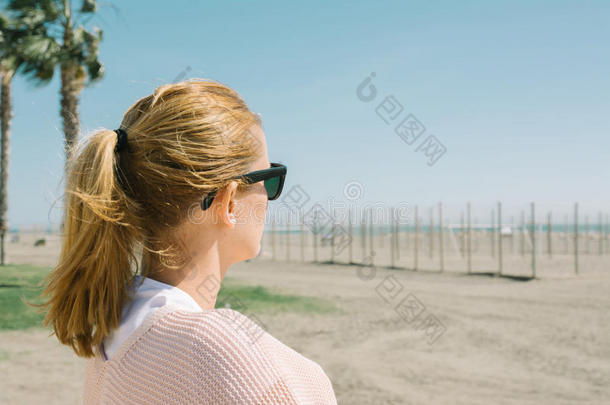 戴太阳镜的金发女孩看着大海，在靠近TH的<strong>风天</strong>