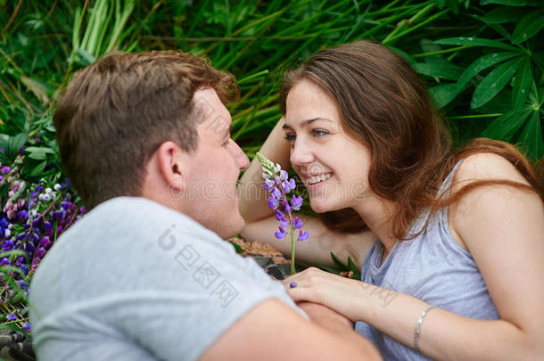 一对相爱的夫妇躺在夏日草地上的草地上