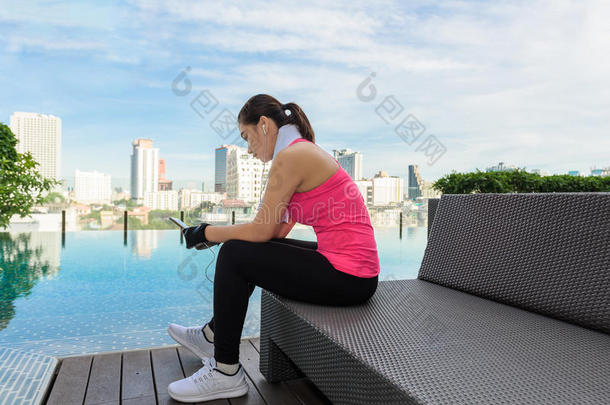 活跃的女孩在游泳池旁边使用智能手机健身
