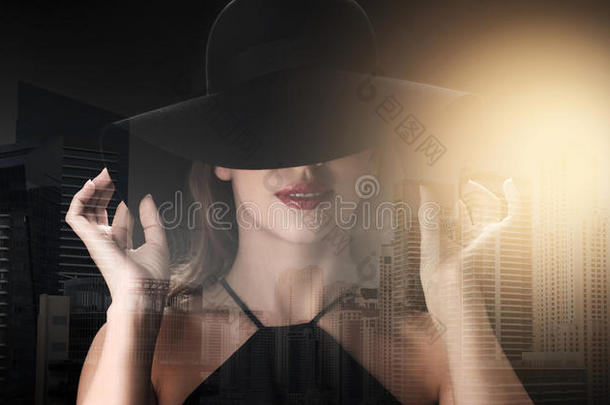 戴黑帽子的漂亮女人在黑暗的背景下