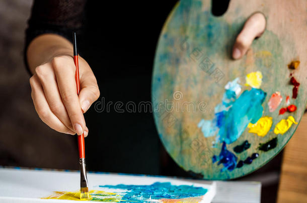 用油画颜料在画布上画女孩的特写。