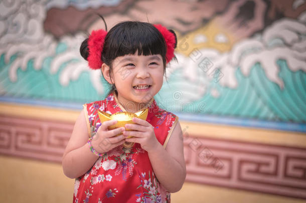 中国女孩穿着传统的中国服装问候，拿着一<strong>枚</strong>金子