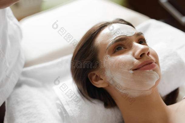 面部皮肤护理。 美丽的女人带着美容面膜在水疗中心