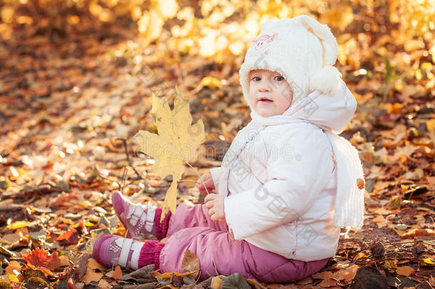 阳光明媚的秋天，公园里带着树叶的可爱的蹒跚学步的女孩