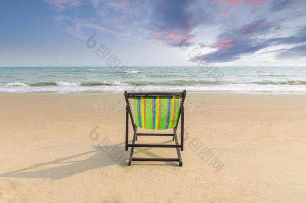 沙滩椅在白沙滩与日落黄昏的天空和复制空间。 暑期背景。 夏季景观概念。 浪漫的