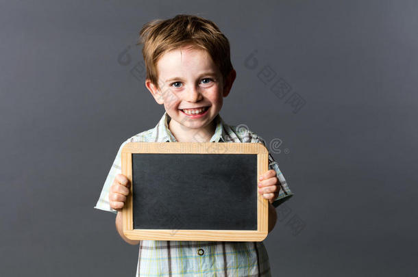 快乐的男学龄前儿童自豪地学习写字板