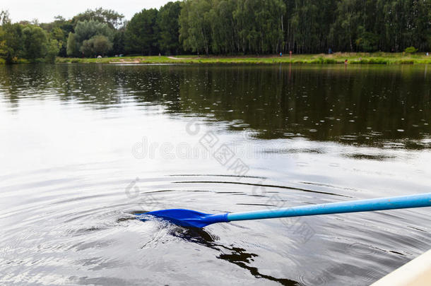 在城市池塘里用桨漂浮在船上