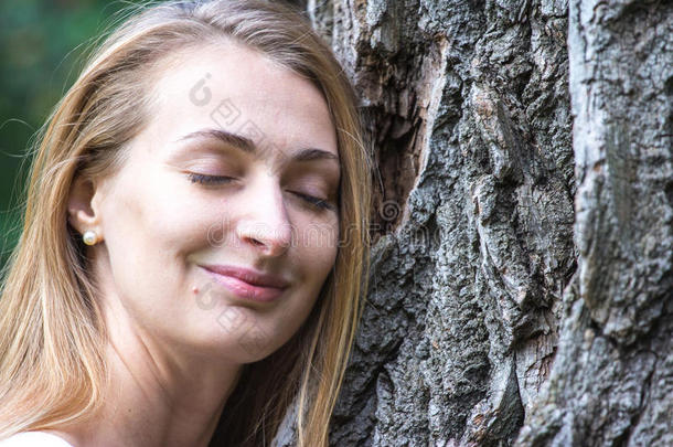 亲近体贴的年轻自然-爱女人拥抱一棵巨大的树